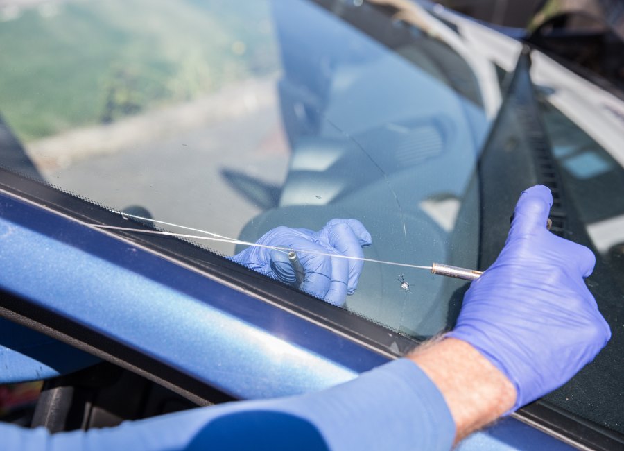 Black car's auto glass maintenance by employee of Perfect Auto Glass in Edmonton. He is expert in Importance of Regular Auto Glass Maintenance