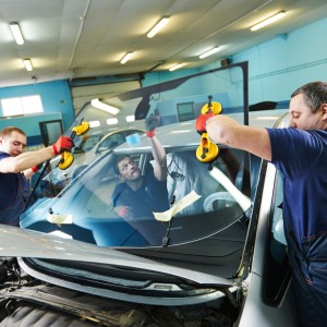 A team of Technicians works together after repairing a Broken Windshield on a car.